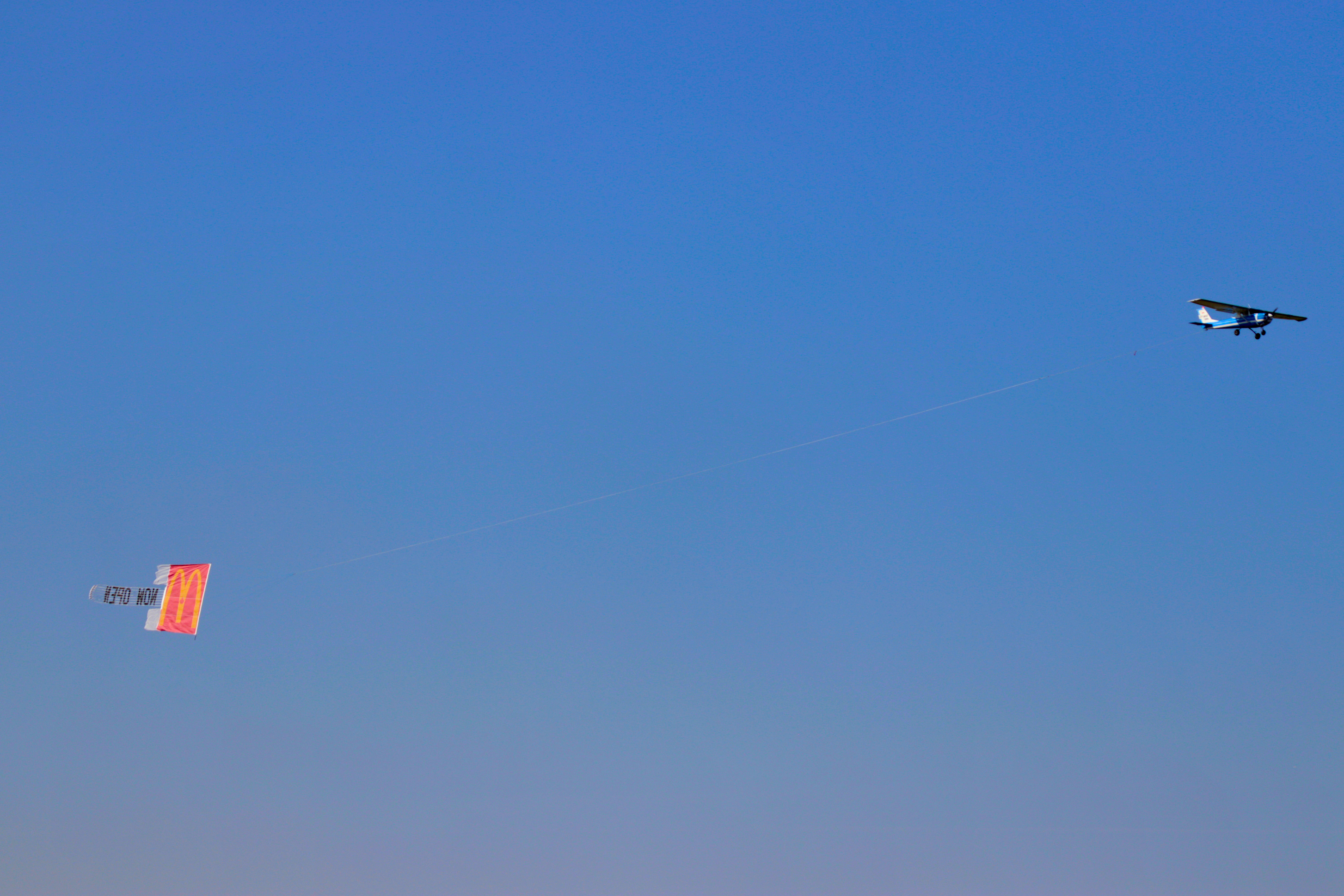 Aircraft towing a McDonald's combo banner across a clear blue sky